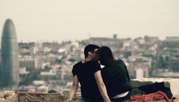 A Man And Woman Kissing On A Ledge