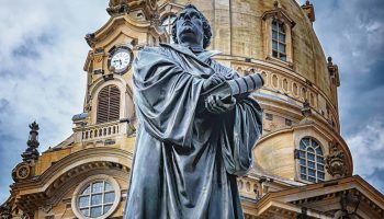 A Statue Of A Man In Front Of A Building