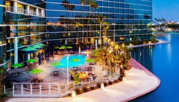 A Pool And Palm Trees Next To A Building