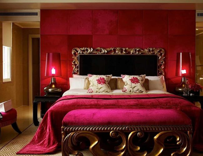 A Bed With A Red Blanket And A Red Lamp
