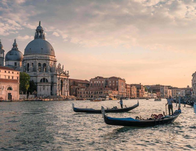 A Group Of People In A Boat On A Body Of Water With A Dome In The Background